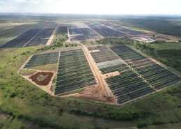 Aerial view of a large solar farm with rows of solar panels across open countryside.