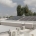 Rooftop with solar panels installed on a flat white building, with air‑conditioning units in the foreground.